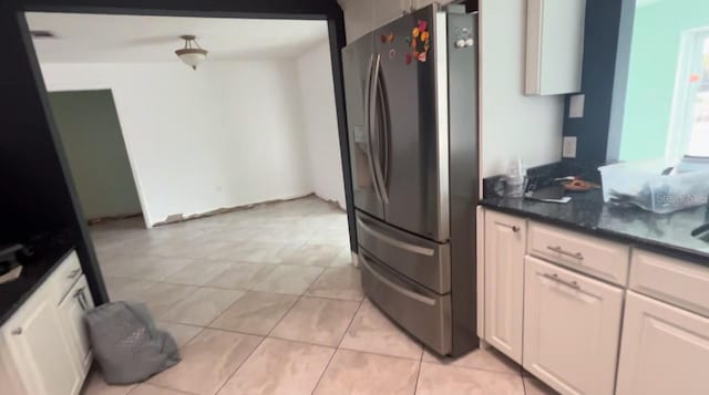 kitchen with stainless steel refrigerator with ice dispenser, white cabinetry, dark stone counters, and light tile patterned flooring