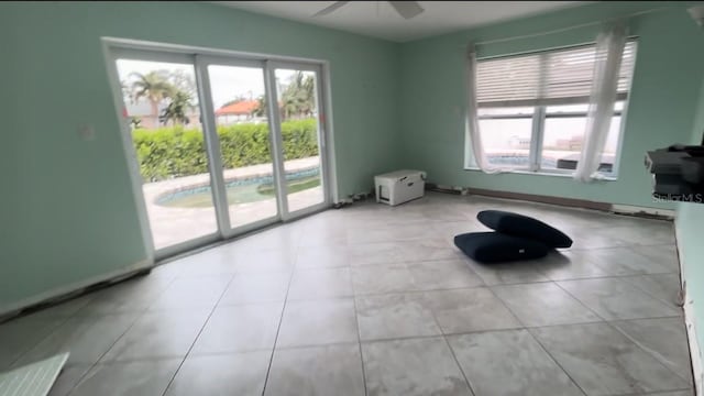 unfurnished room featuring ceiling fan, light tile patterned floors, and a wealth of natural light