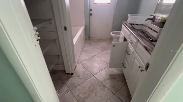 bathroom with tile patterned flooring, vanity, toilet, and a bath