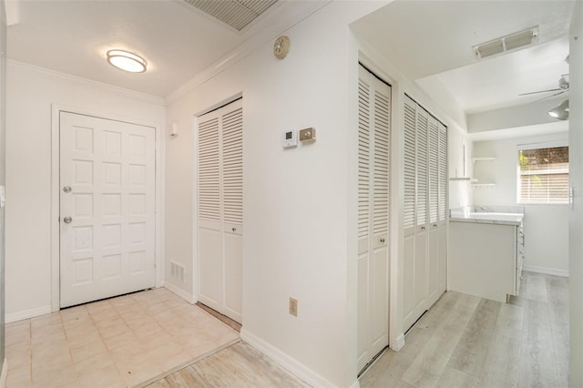 hall with light wood-type flooring and ornamental molding