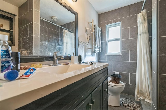 bathroom featuring a textured ceiling, vanity, toilet, and tile walls