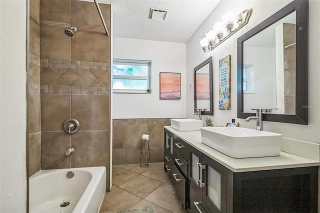 bathroom featuring vanity, tile patterned flooring, tiled shower / bath combo, a textured ceiling, and tile walls