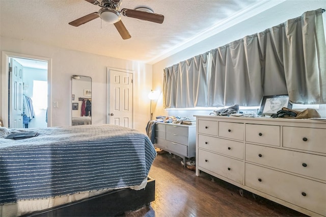 bedroom with a textured ceiling, ceiling fan, dark wood-type flooring, and a closet