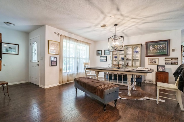 dining space featuring dark hardwood / wood-style flooring, a textured ceiling, and an inviting chandelier