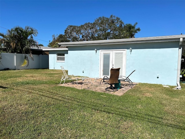 rear view of house with french doors, a patio area, and a lawn