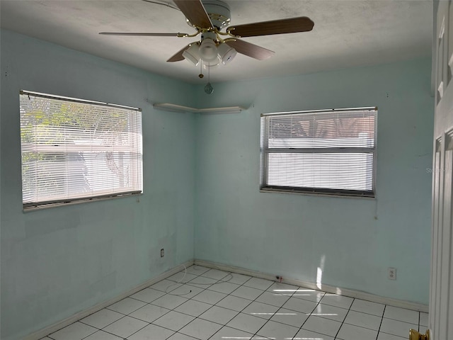 empty room with ceiling fan and light tile patterned floors