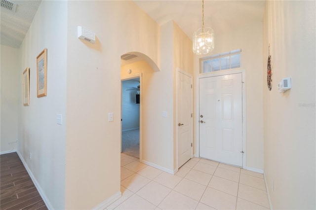 tiled entryway with a textured ceiling and a notable chandelier