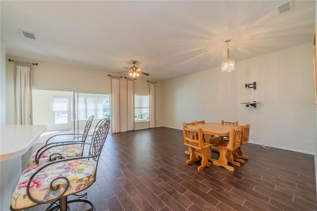 dining room featuring ceiling fan with notable chandelier and dark hardwood / wood-style flooring