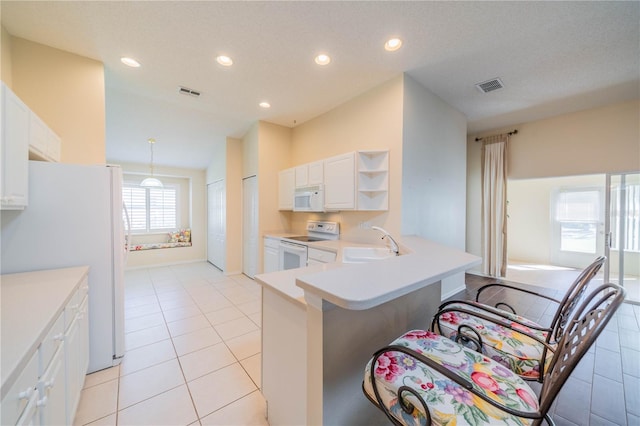 kitchen with kitchen peninsula, white appliances, light tile patterned floors, pendant lighting, and white cabinetry