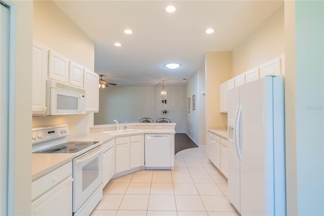 kitchen with kitchen peninsula, white appliances, sink, light tile patterned floors, and white cabinets