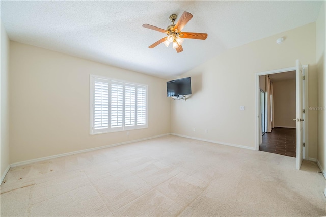 spare room with a textured ceiling, ceiling fan, light colored carpet, and lofted ceiling