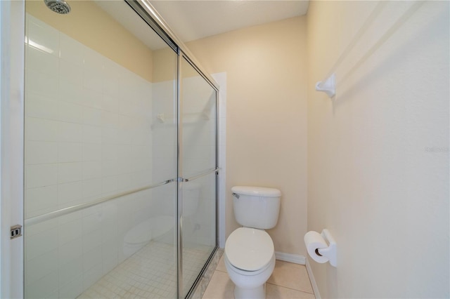 bathroom featuring tile patterned flooring, a shower with door, and toilet