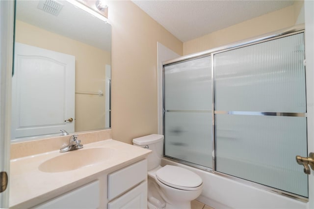 full bathroom featuring tile patterned flooring, bath / shower combo with glass door, a textured ceiling, toilet, and vanity