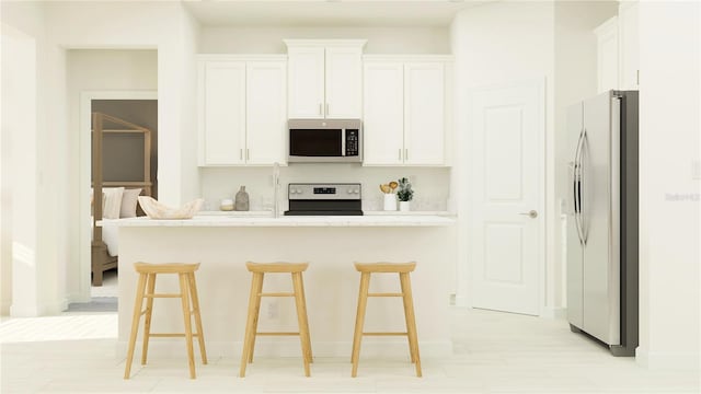 kitchen with stainless steel appliances, light stone countertops, a kitchen bar, and white cabinetry