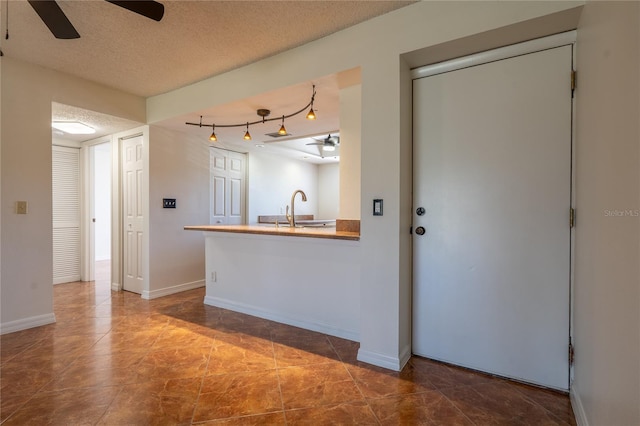 kitchen featuring ceiling fan, sink, and a textured ceiling