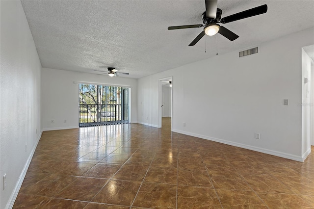 empty room with ceiling fan, dark tile patterned floors, and a textured ceiling