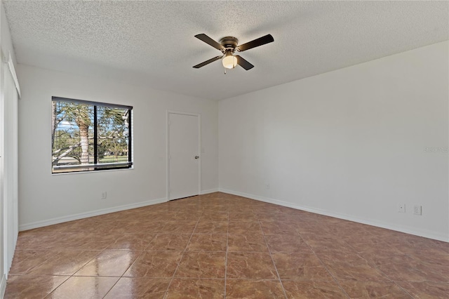 empty room with ceiling fan, light tile patterned floors, and a textured ceiling