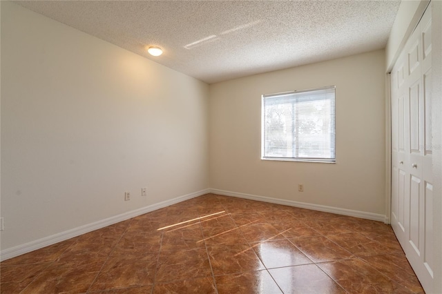 tiled spare room with a textured ceiling