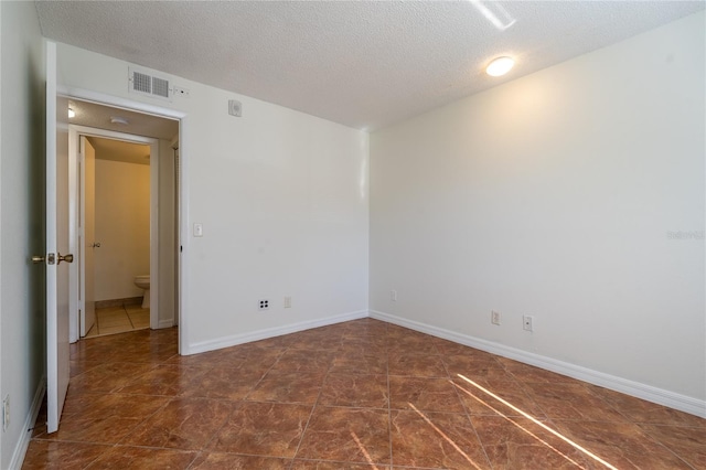 unfurnished room with dark tile patterned floors and a textured ceiling