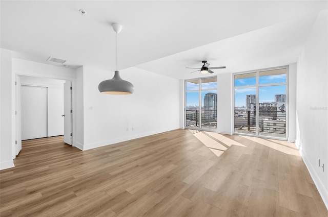 unfurnished living room featuring expansive windows, light hardwood / wood-style floors, and ceiling fan