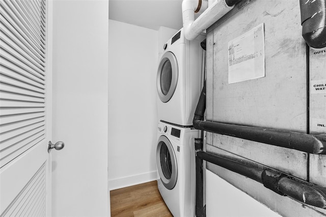 laundry area featuring hardwood / wood-style floors and stacked washing maching and dryer