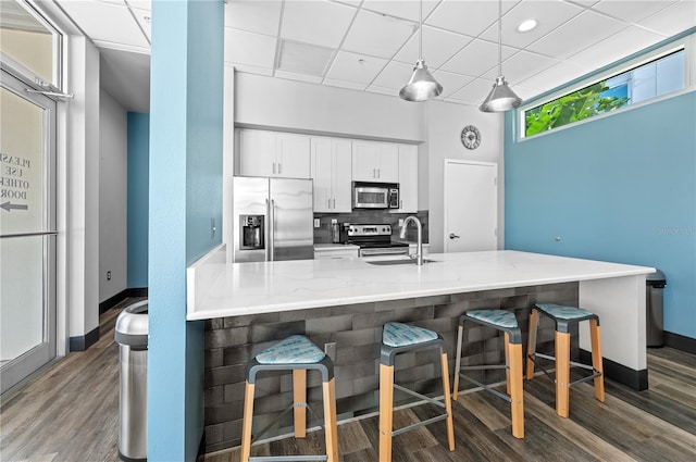 kitchen featuring white cabinets, dark hardwood / wood-style flooring, a breakfast bar area, and appliances with stainless steel finishes