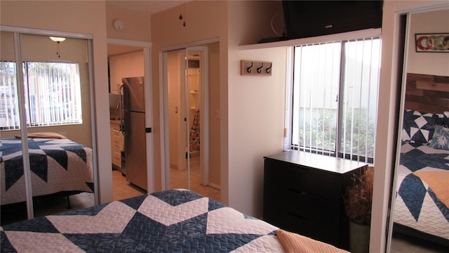 bedroom featuring multiple windows, stainless steel fridge, a closet, and light tile patterned floors