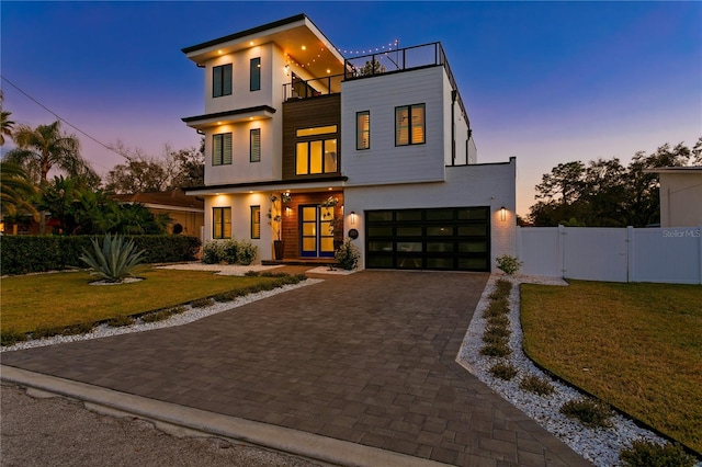 contemporary home featuring a lawn, a balcony, and a garage