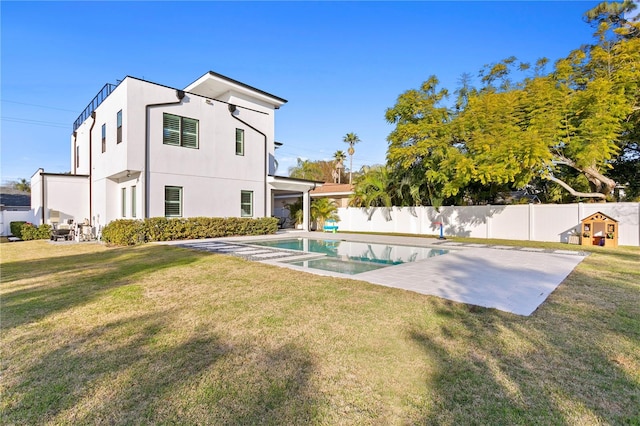 rear view of property featuring a fenced in pool, a yard, and a patio