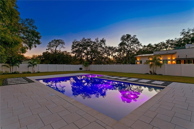 pool at dusk with a yard and a patio area