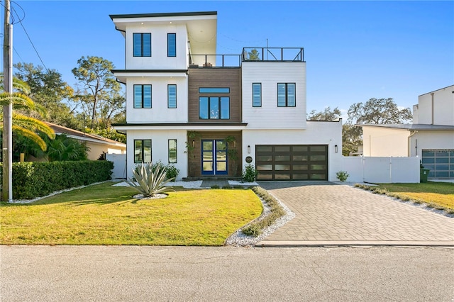 contemporary home featuring a garage, a balcony, a front yard, and french doors