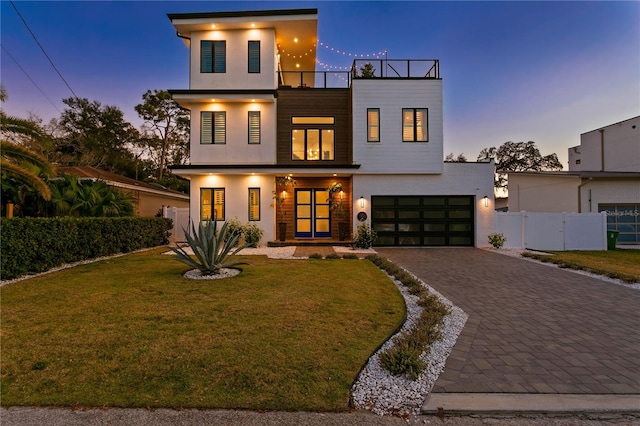 view of front facade with a balcony, a garage, and a lawn