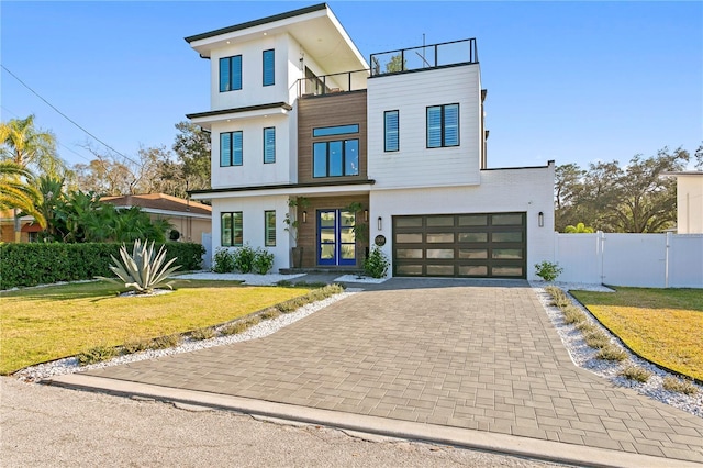 contemporary home featuring a garage, a balcony, and a front lawn