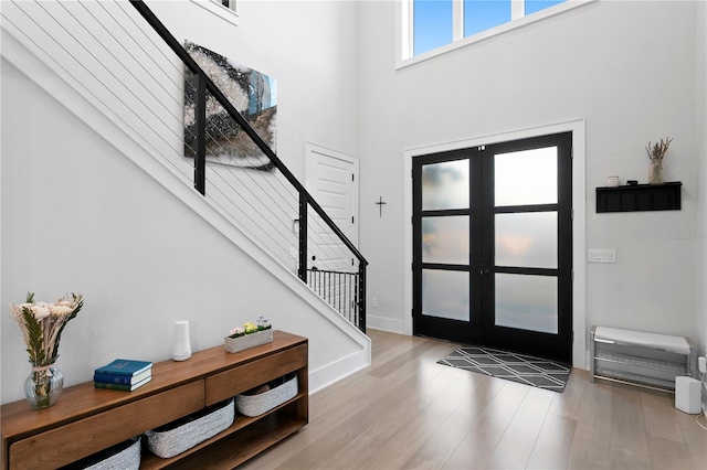 entryway featuring light hardwood / wood-style flooring, a high ceiling, and french doors