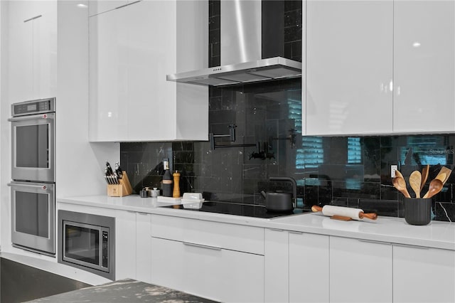 kitchen with white cabinets, appliances with stainless steel finishes, and wall chimney exhaust hood