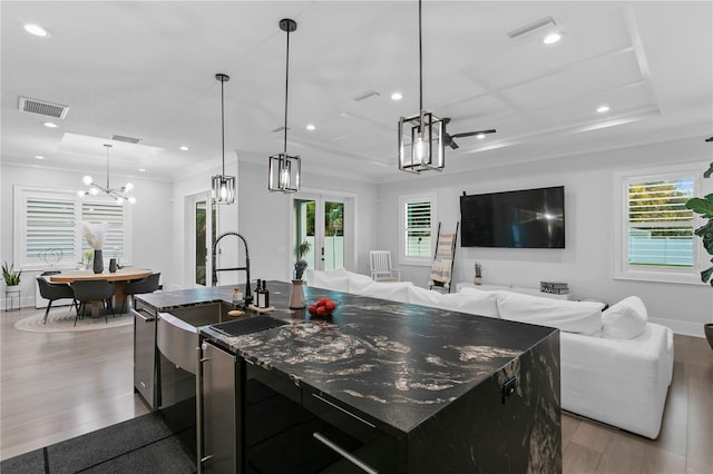 kitchen featuring a kitchen island with sink, sink, hanging light fixtures, light wood-type flooring, and plenty of natural light