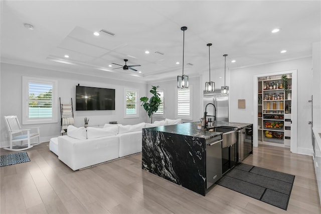 kitchen with appliances with stainless steel finishes, ceiling fan, a kitchen island with sink, dark stone countertops, and hanging light fixtures