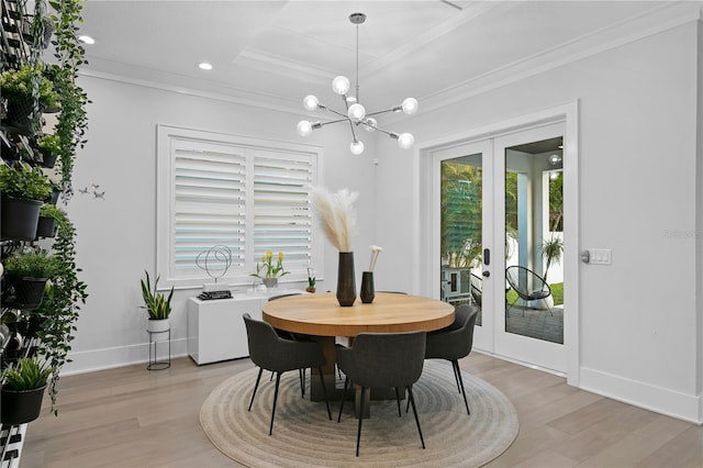 dining area featuring french doors, a tray ceiling, crown molding, a notable chandelier, and light hardwood / wood-style floors