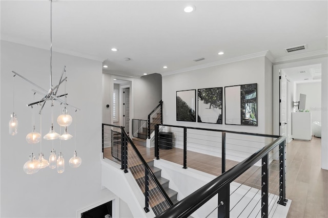 hall featuring a notable chandelier, light hardwood / wood-style floors, and ornamental molding