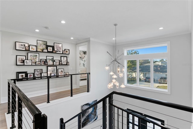 corridor with hardwood / wood-style floors, ornamental molding, and an inviting chandelier