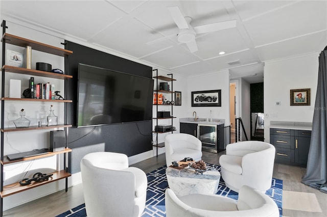 living room with indoor bar, light wood-type flooring, ceiling fan, and coffered ceiling