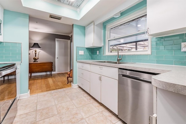 kitchen with decorative backsplash, appliances with stainless steel finishes, sink, white cabinets, and light hardwood / wood-style floors