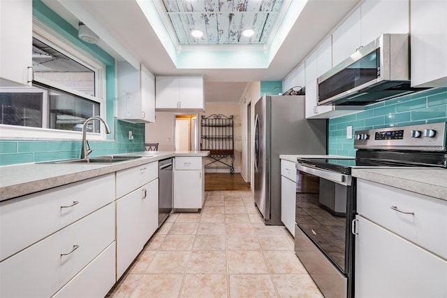 kitchen with a tray ceiling, white cabinets, and appliances with stainless steel finishes