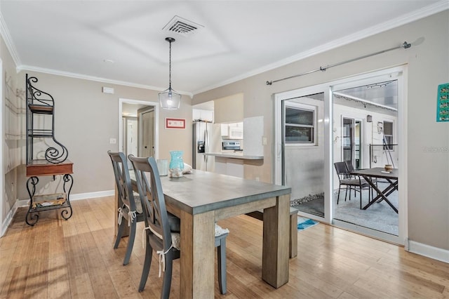 dining space featuring crown molding and light hardwood / wood-style flooring