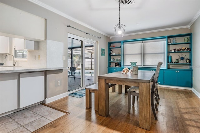 dining space with light hardwood / wood-style floors, crown molding, and sink