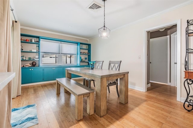 dining room with light hardwood / wood-style flooring and crown molding