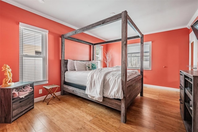 bedroom featuring multiple windows, hardwood / wood-style floors, and ornamental molding