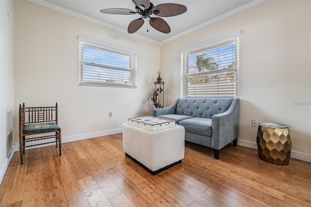 living area featuring hardwood / wood-style floors, ceiling fan, and crown molding