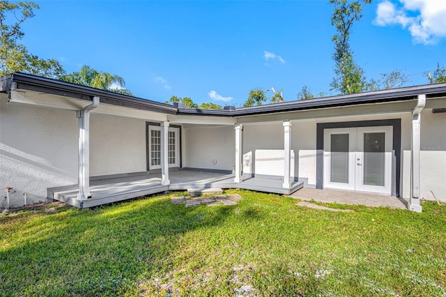 rear view of property featuring a wooden deck, a yard, and french doors