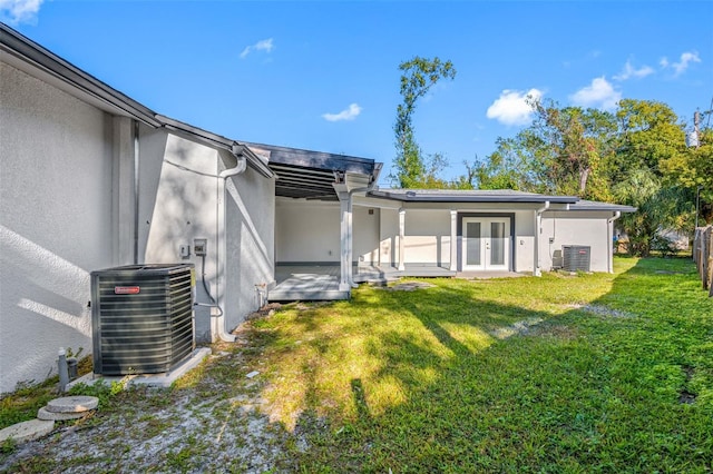 back of house with a yard, central AC unit, and french doors